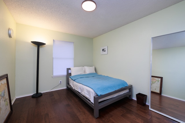 bedroom featuring a textured ceiling and dark hardwood / wood-style floors