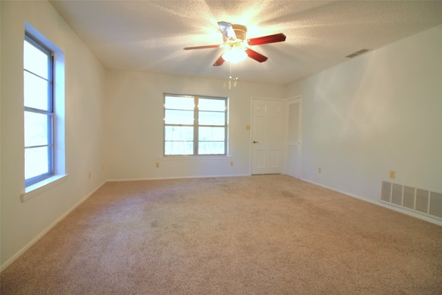 empty room with a textured ceiling, carpet floors, and ceiling fan