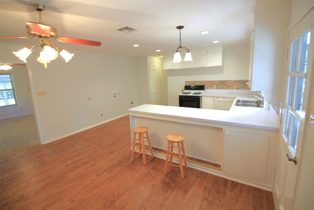 kitchen with a wealth of natural light, white cabinetry, white stove, and kitchen peninsula