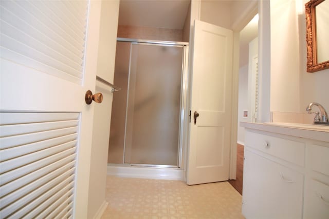 bathroom featuring a shower with door and vanity