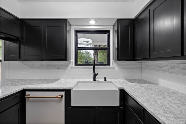 kitchen with stainless steel dishwasher, sink, backsplash, and light stone counters