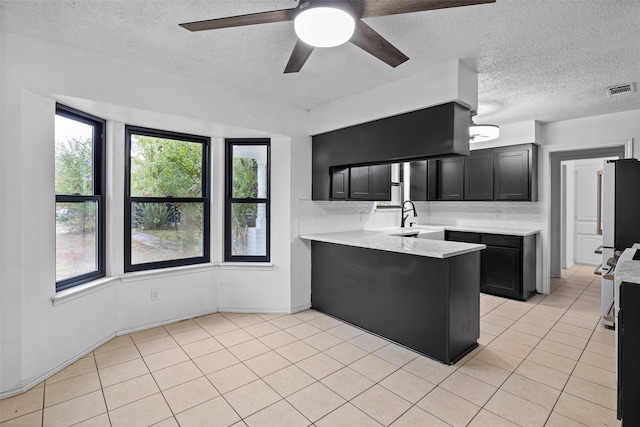 kitchen featuring kitchen peninsula, light tile patterned floors, tasteful backsplash, and ceiling fan