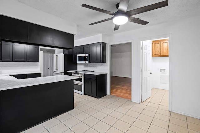 kitchen with appliances with stainless steel finishes, ceiling fan, a textured ceiling, light tile patterned floors, and decorative backsplash