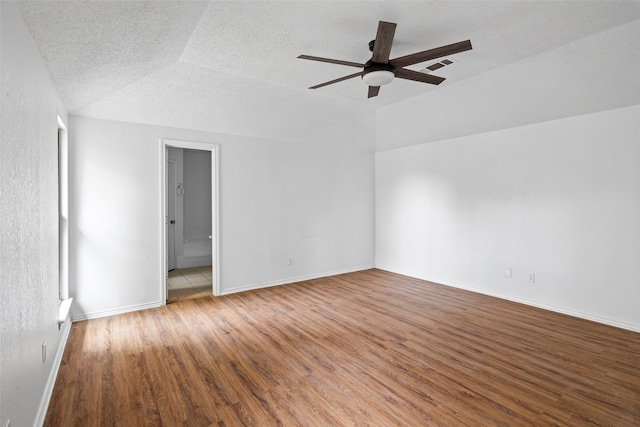 empty room with a textured ceiling, lofted ceiling, hardwood / wood-style flooring, and ceiling fan