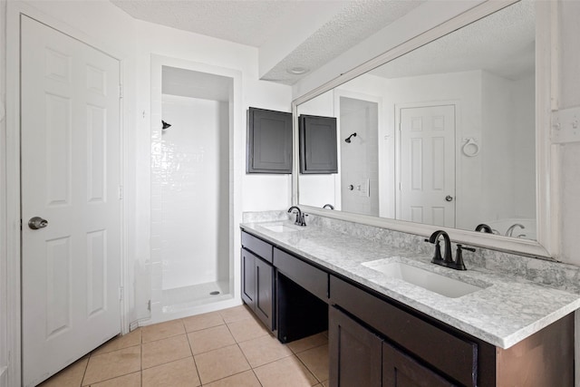 bathroom featuring vanity, a textured ceiling, tile patterned floors, and tiled shower