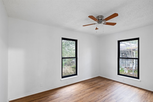 empty room with a textured ceiling, hardwood / wood-style flooring, and a healthy amount of sunlight