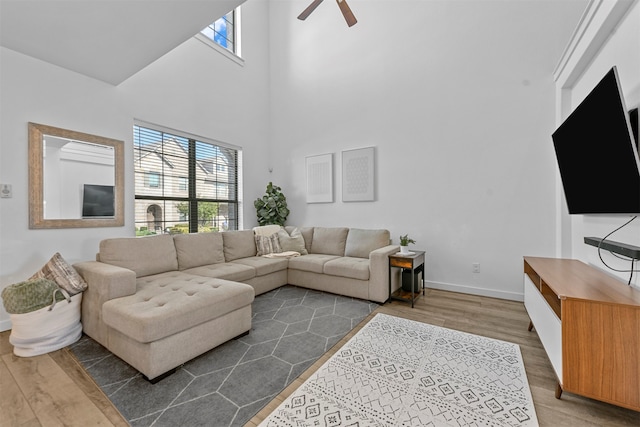 living room with hardwood / wood-style floors, a towering ceiling, and ceiling fan