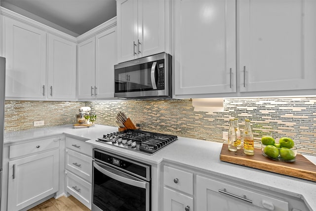 kitchen featuring stainless steel appliances, white cabinets, light hardwood / wood-style flooring, and tasteful backsplash