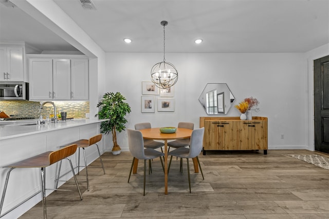 dining space with sink, a notable chandelier, and light hardwood / wood-style floors