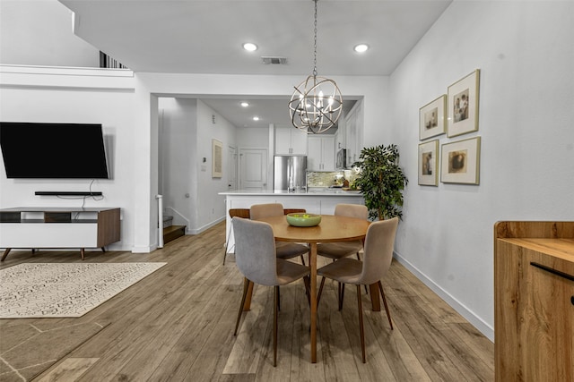 dining space with light hardwood / wood-style floors and an inviting chandelier