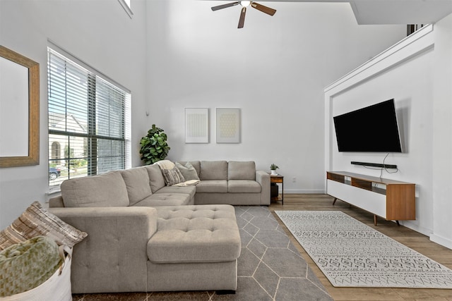 living room featuring dark wood-type flooring, a high ceiling, and ceiling fan