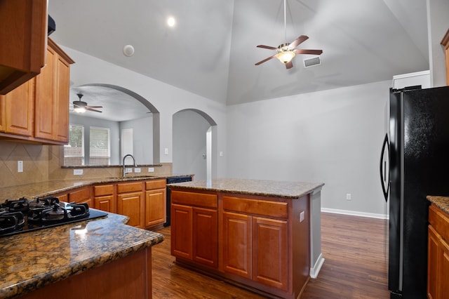 kitchen with sink, black appliances, a center island, dark wood-type flooring, and decorative backsplash