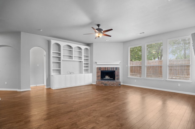 unfurnished living room featuring hardwood / wood-style floors, ceiling fan, and a brick fireplace