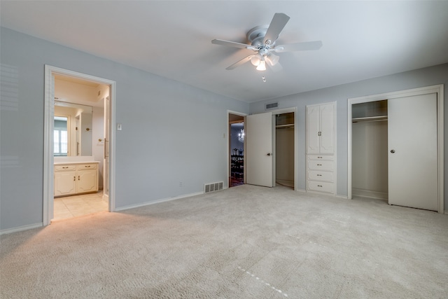 unfurnished bedroom with multiple closets, light carpet, ceiling fan, and ensuite bathroom