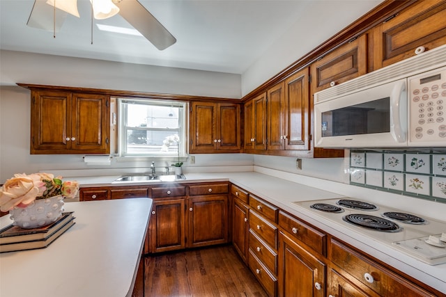 kitchen featuring dark wood-type flooring, white appliances, ceiling fan, and sink