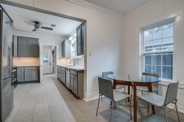 kitchen with stainless steel appliances, light countertops, decorative backsplash, gray cabinetry, and a sink