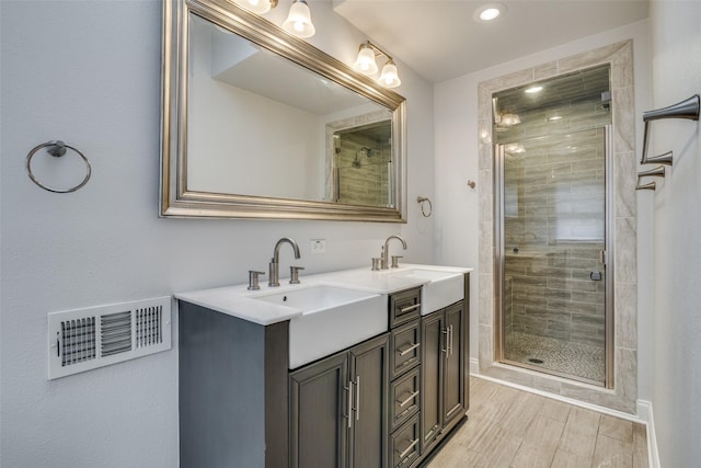 full bath featuring a stall shower, visible vents, a sink, and double vanity