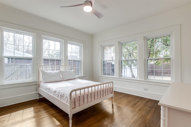 bedroom with dark wood finished floors, a ceiling fan, and baseboards