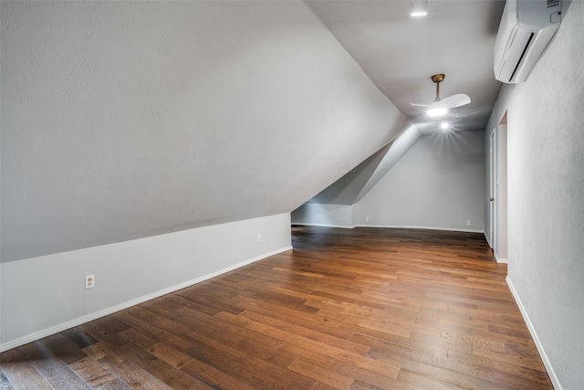 additional living space with an AC wall unit, wood finished floors, and baseboards