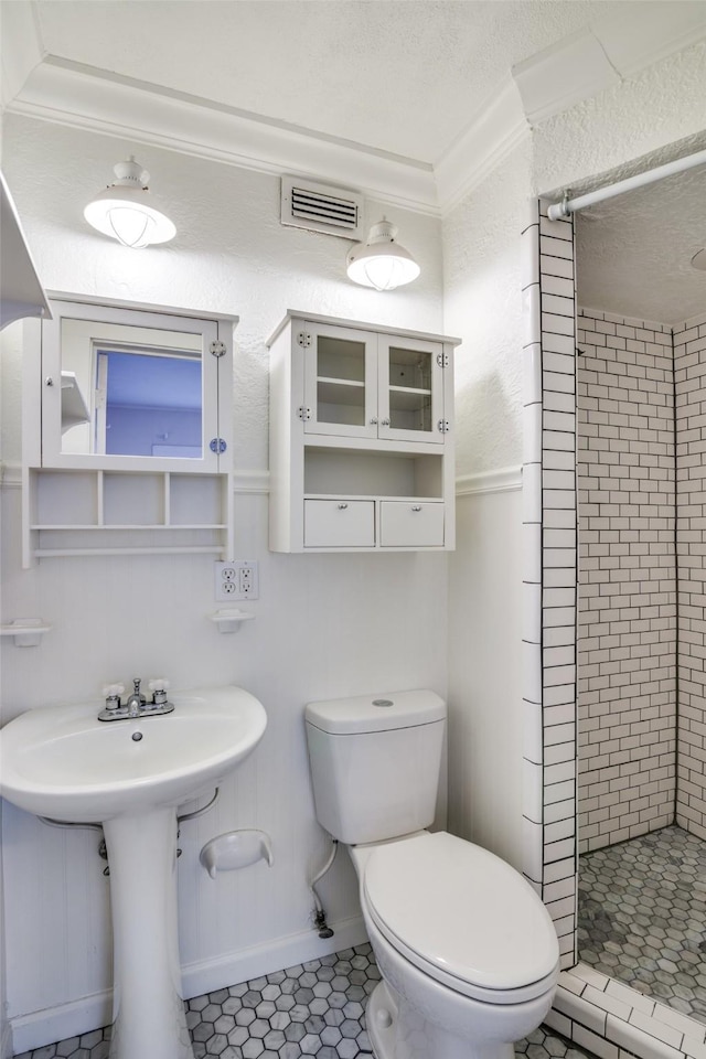 bathroom with toilet, a sink, visible vents, a stall shower, and crown molding