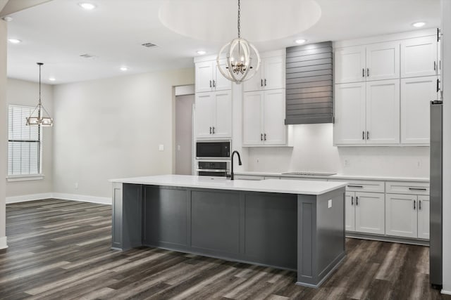 kitchen featuring a kitchen island with sink, white cabinetry, decorative light fixtures, and dark hardwood / wood-style flooring