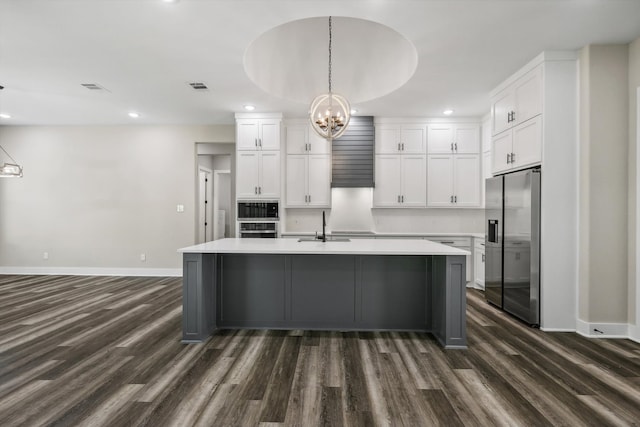 kitchen featuring dark wood-type flooring, stainless steel fridge, white cabinets, and hanging light fixtures