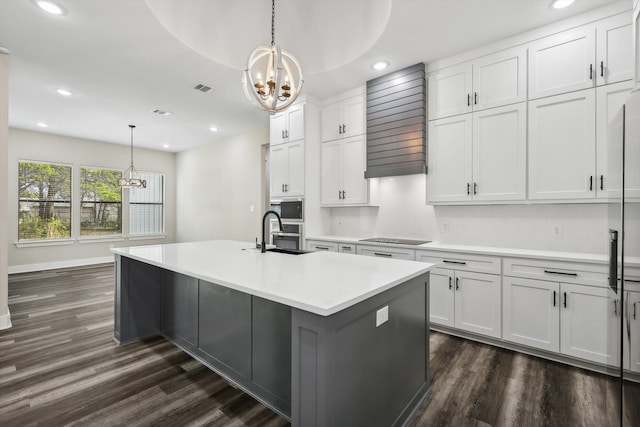 kitchen featuring white cabinetry, dark hardwood / wood-style flooring, pendant lighting, sink, and a kitchen island with sink