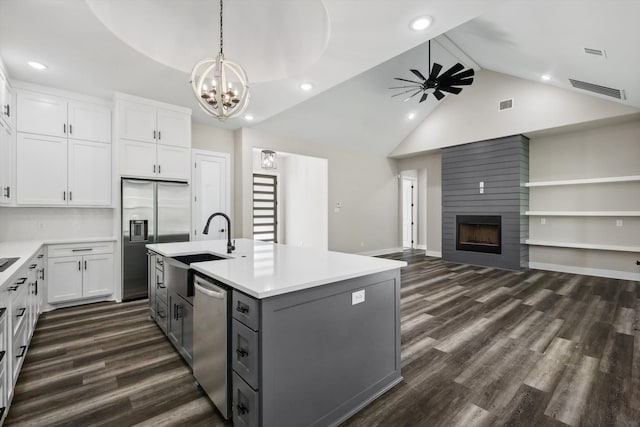 kitchen featuring white cabinets, dark wood-type flooring, a center island with sink, and a large fireplace