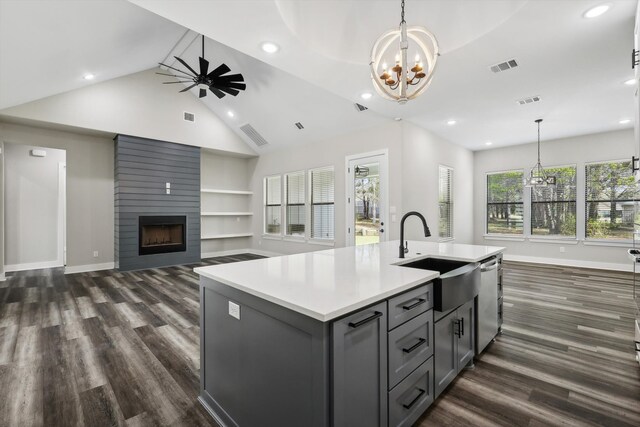 kitchen featuring dark hardwood / wood-style floors, sink, a center island with sink, and a fireplace