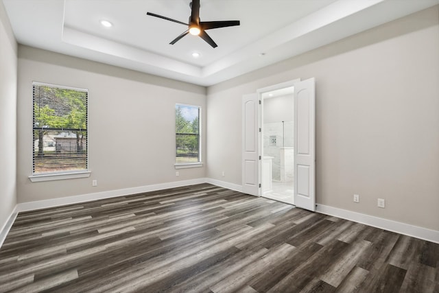 unfurnished bedroom featuring dark hardwood / wood-style flooring, multiple windows, ceiling fan, and ensuite bathroom