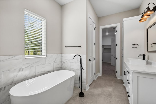 bathroom featuring tile patterned floors, vanity, a bathing tub, and tile walls