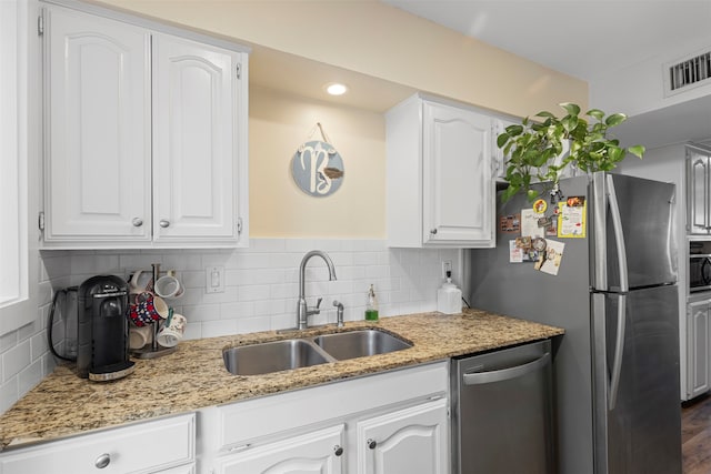 kitchen with dark wood-type flooring, sink, light stone countertops, white cabinetry, and appliances with stainless steel finishes