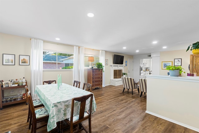 dining room with a brick fireplace and hardwood / wood-style floors