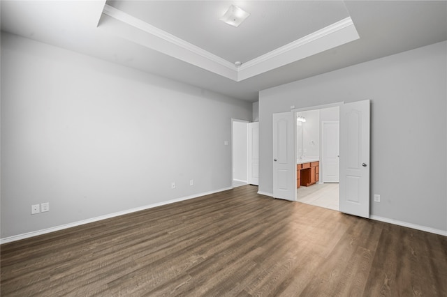 unfurnished bedroom with dark hardwood / wood-style flooring, a tray ceiling, ornamental molding, and ensuite bathroom