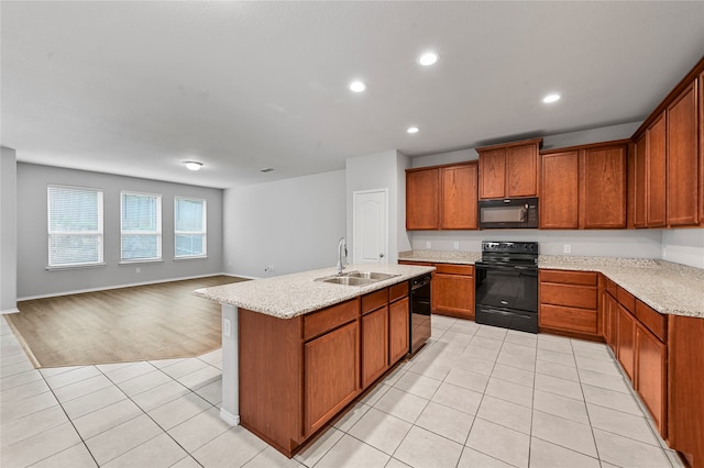 kitchen featuring sink, black appliances, light stone countertops, light tile patterned floors, and a kitchen island with sink