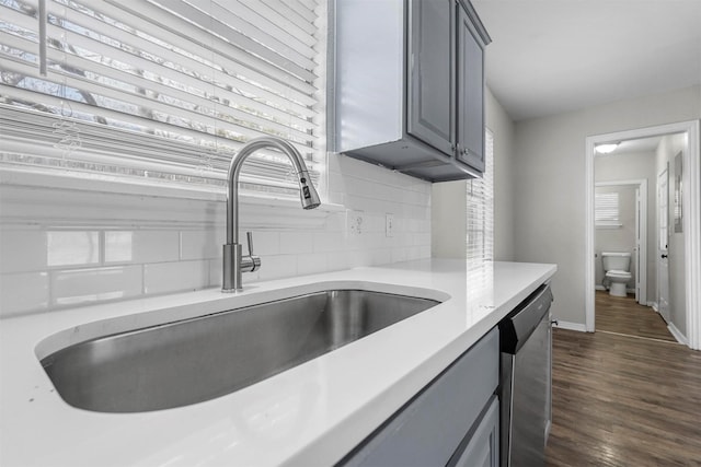 kitchen featuring sink, gray cabinetry, tasteful backsplash, stainless steel dishwasher, and dark hardwood / wood-style flooring