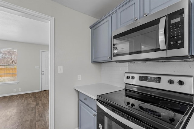 kitchen featuring dark wood-type flooring, appliances with stainless steel finishes, gray cabinets, and backsplash