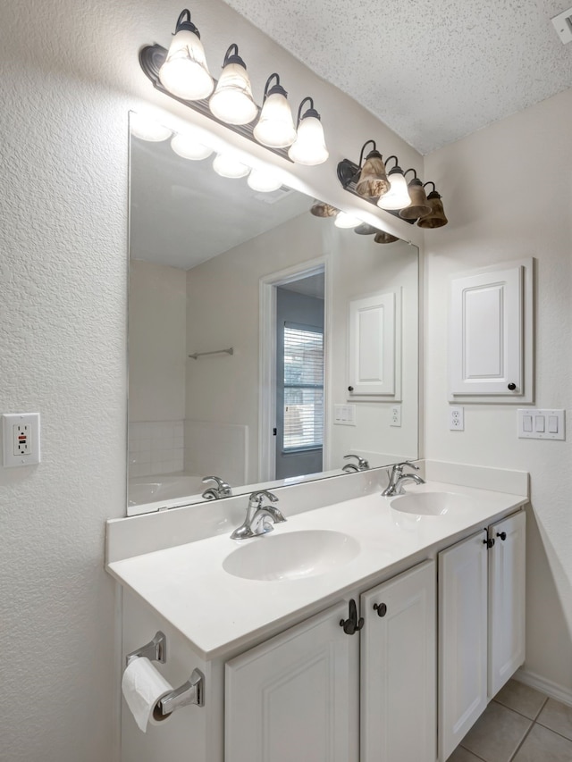 bathroom featuring vanity, a textured ceiling, tile patterned flooring, and a tub