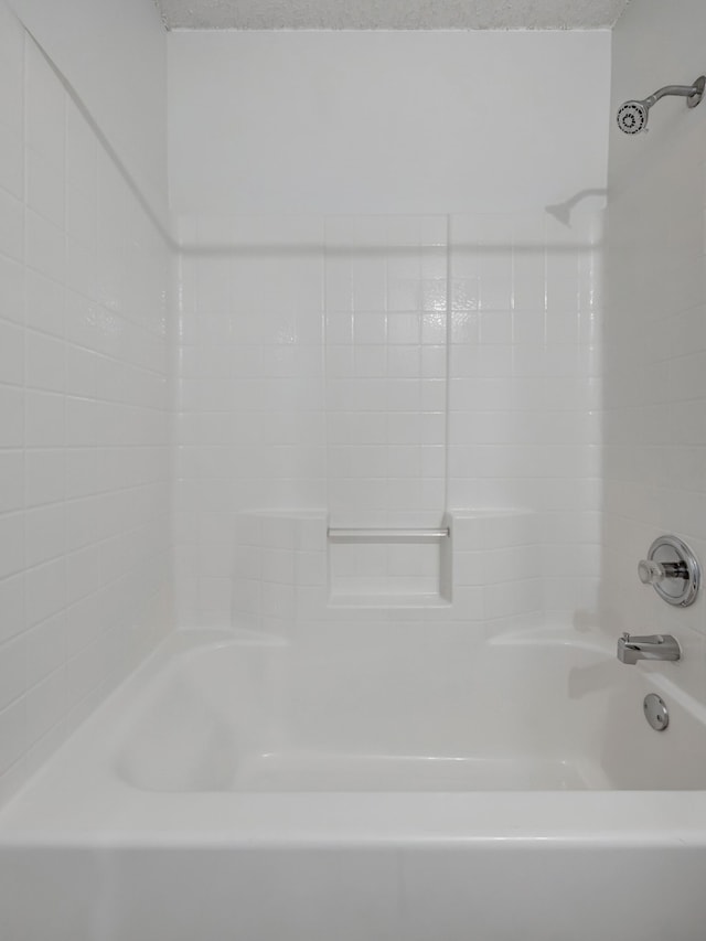 bathroom with a textured ceiling and shower / tub combination