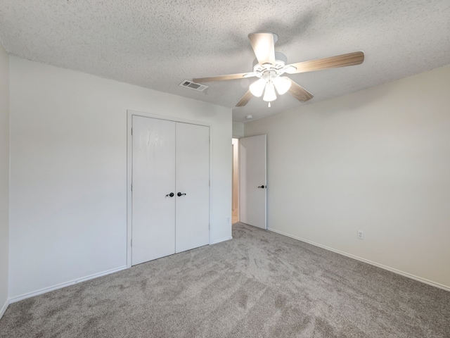 unfurnished bedroom with ceiling fan, carpet flooring, a closet, and a textured ceiling