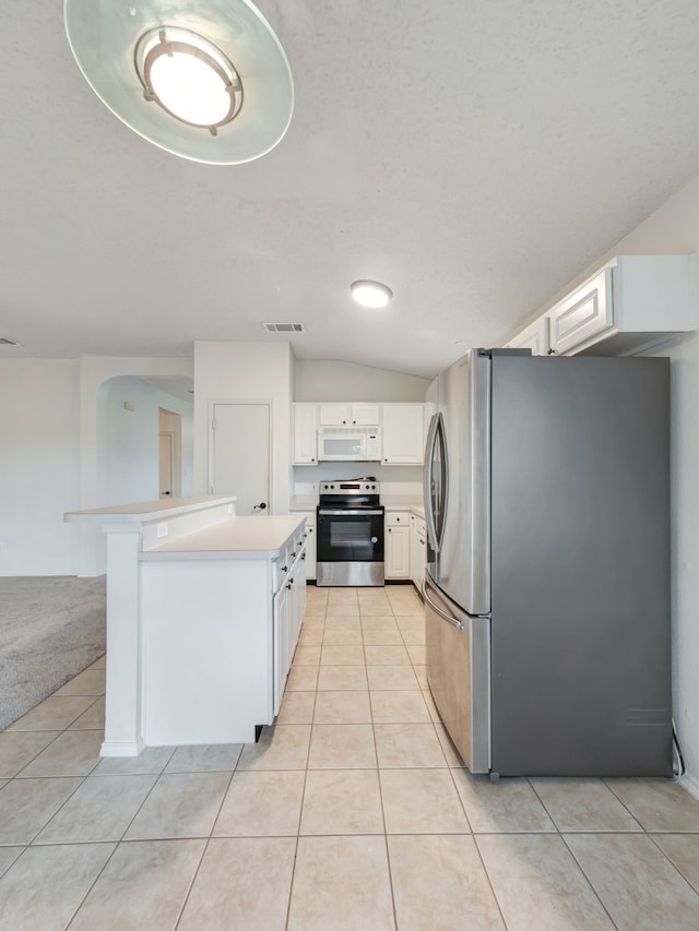 kitchen featuring white cabinetry, vaulted ceiling, light tile patterned floors, and stainless steel appliances