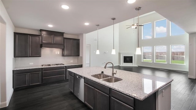 kitchen with dark hardwood / wood-style flooring, sink, an island with sink, pendant lighting, and appliances with stainless steel finishes