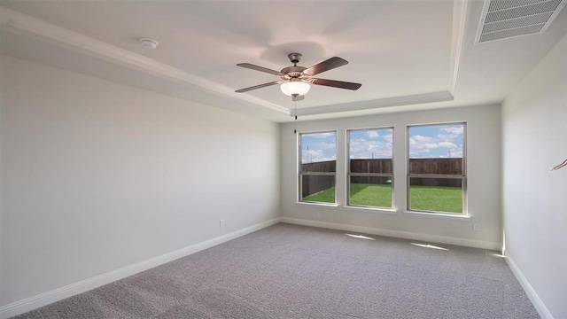 carpeted empty room with ceiling fan and a raised ceiling