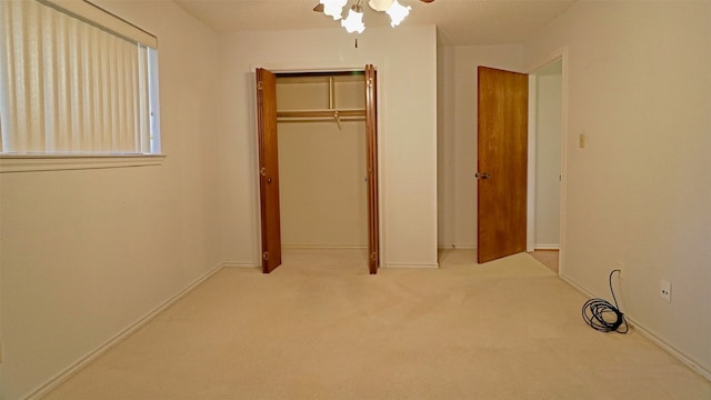 unfurnished bedroom with ceiling fan, light colored carpet, and a closet