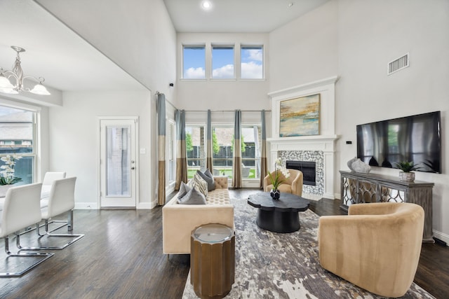 living room with dark hardwood / wood-style floors, a fireplace, a high ceiling, and an inviting chandelier