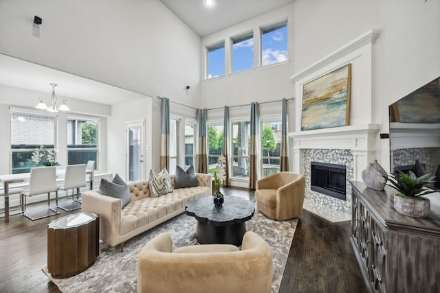 living room featuring a tile fireplace, a high ceiling, dark wood-type flooring, and a notable chandelier