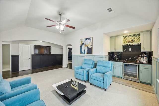 carpeted living room with ceiling fan, beverage cooler, lofted ceiling, and indoor wet bar