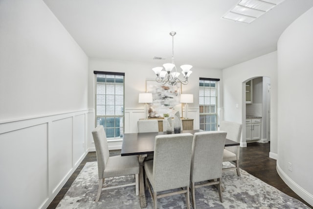 dining area with dark wood-type flooring, a healthy amount of sunlight, and a notable chandelier