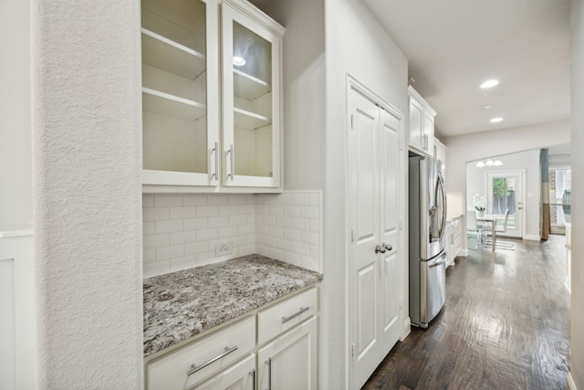 interior space with white cabinets, stainless steel refrigerator with ice dispenser, decorative backsplash, light stone counters, and dark hardwood / wood-style flooring