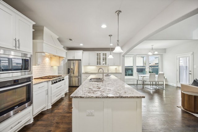 kitchen with appliances with stainless steel finishes, backsplash, sink, a center island with sink, and white cabinetry